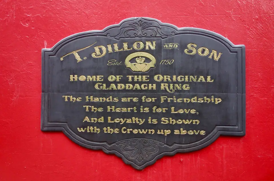 Cartel de la joyería T. Dillon and Son en Galway, que explica el significado del Claddagh: manos por amistad, corazón por amor y corona por lealtad