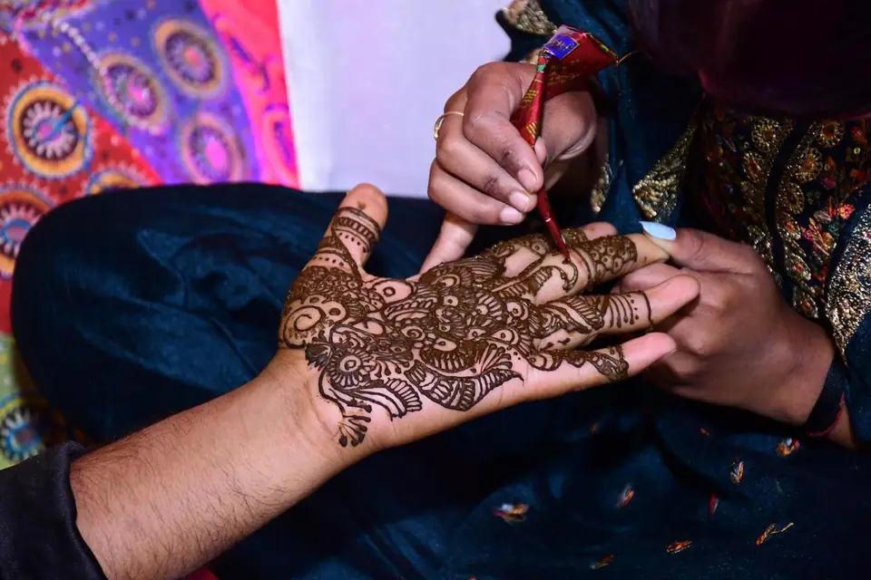Artista aplicando henna con un cono sobre la mano