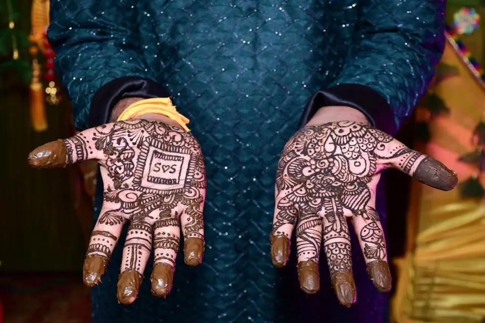 Manos con henna recién aplicada en una ceremonia