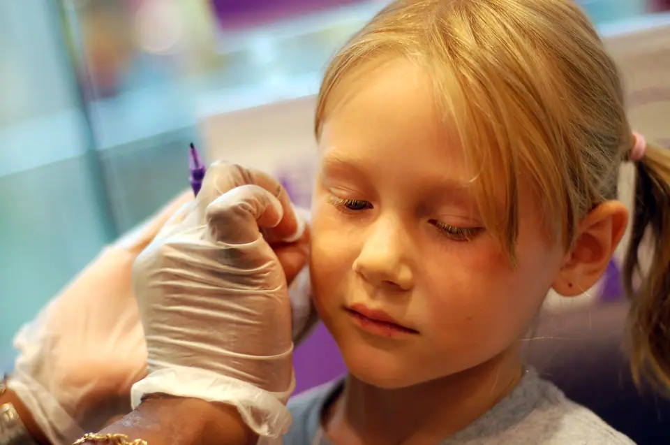 Niña recibiendo un piercing de lóbulo con pistola perforadora
