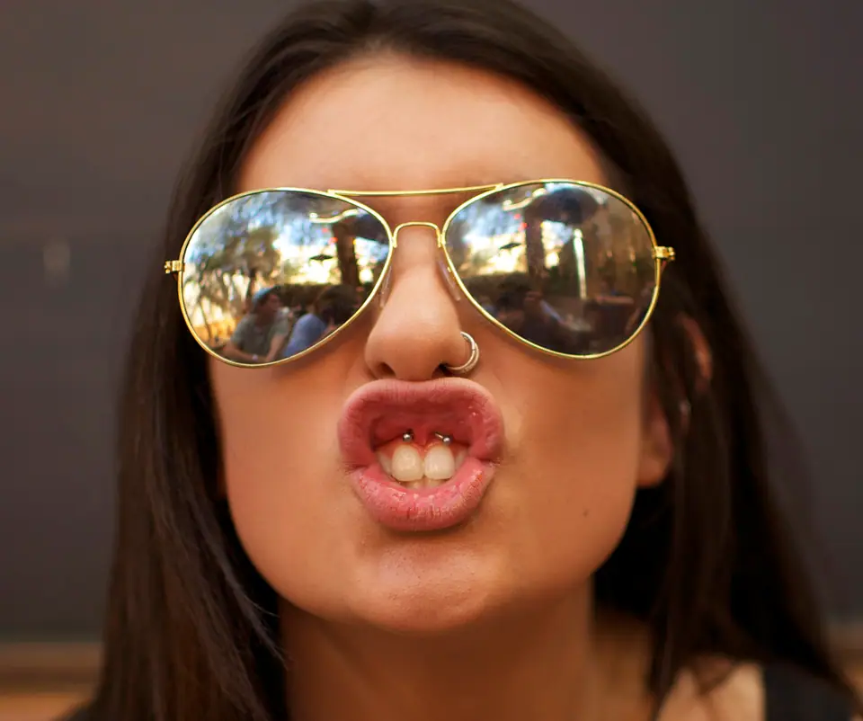 Piercing smiley: una argolla pequeña atraviesa el frenillo labial superior, visible solo al levantar el labio