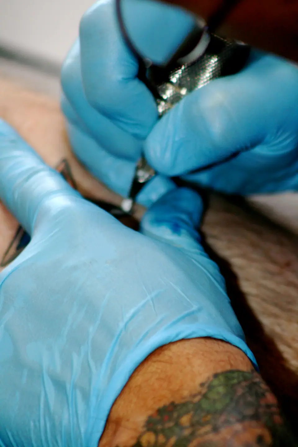 Tatuador trabajando con guantes de látex, parte del protocolo de bioseguridad de un estudio regulado