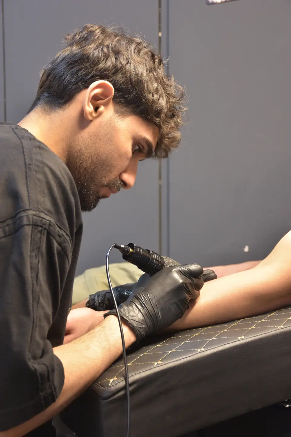 Un tatuador trabaja sobre el brazo de un cliente en un estudio