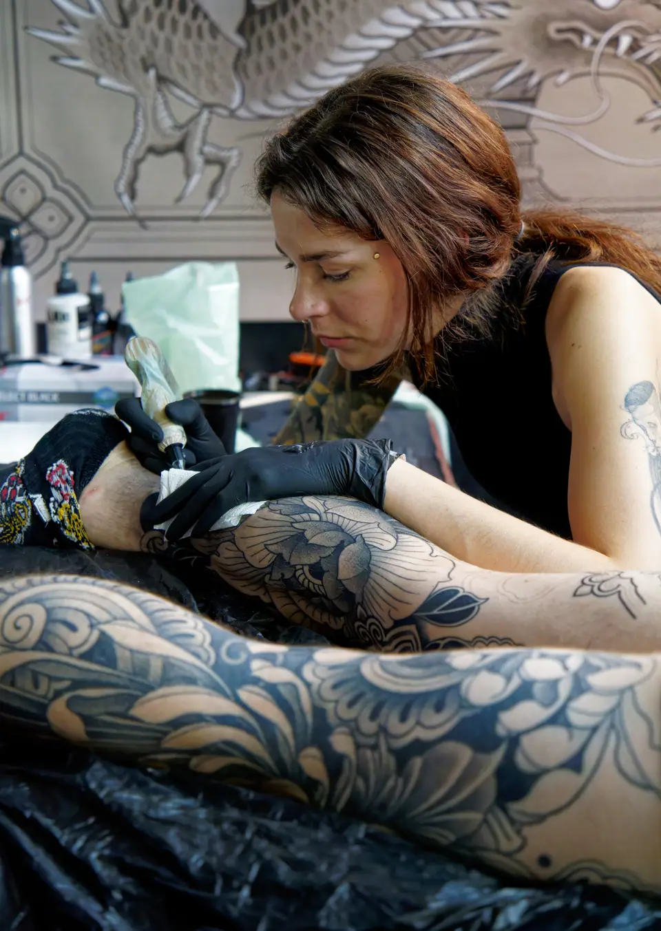 Tatuadora profesional trabajando en un tatuaje de pierna