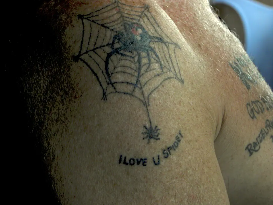 Tatuaje de una araña sobre su telaraña en el hombro