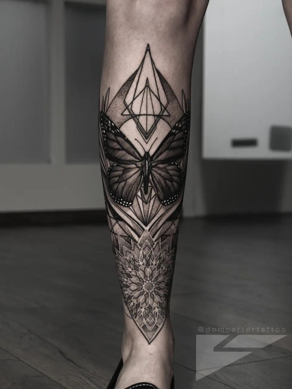 Tatuaje blackwork geométrico de mariposa en la pierna