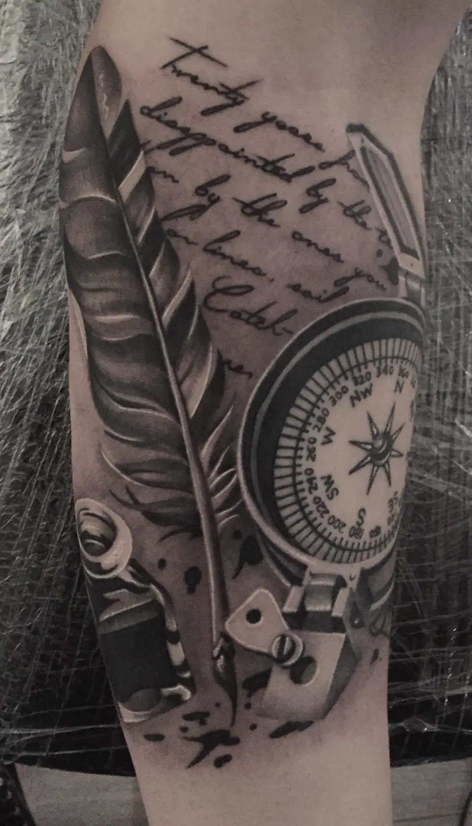 Tatuaje de brújula y pluma en el antebrazo