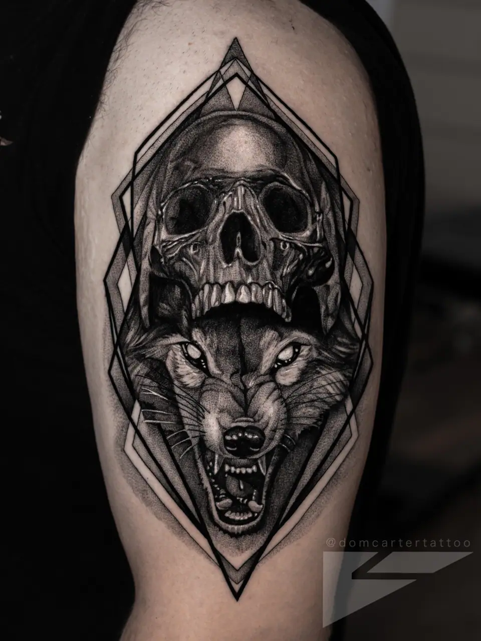 Tatuaje de calavera y lobo en el brazo, estilo dark art