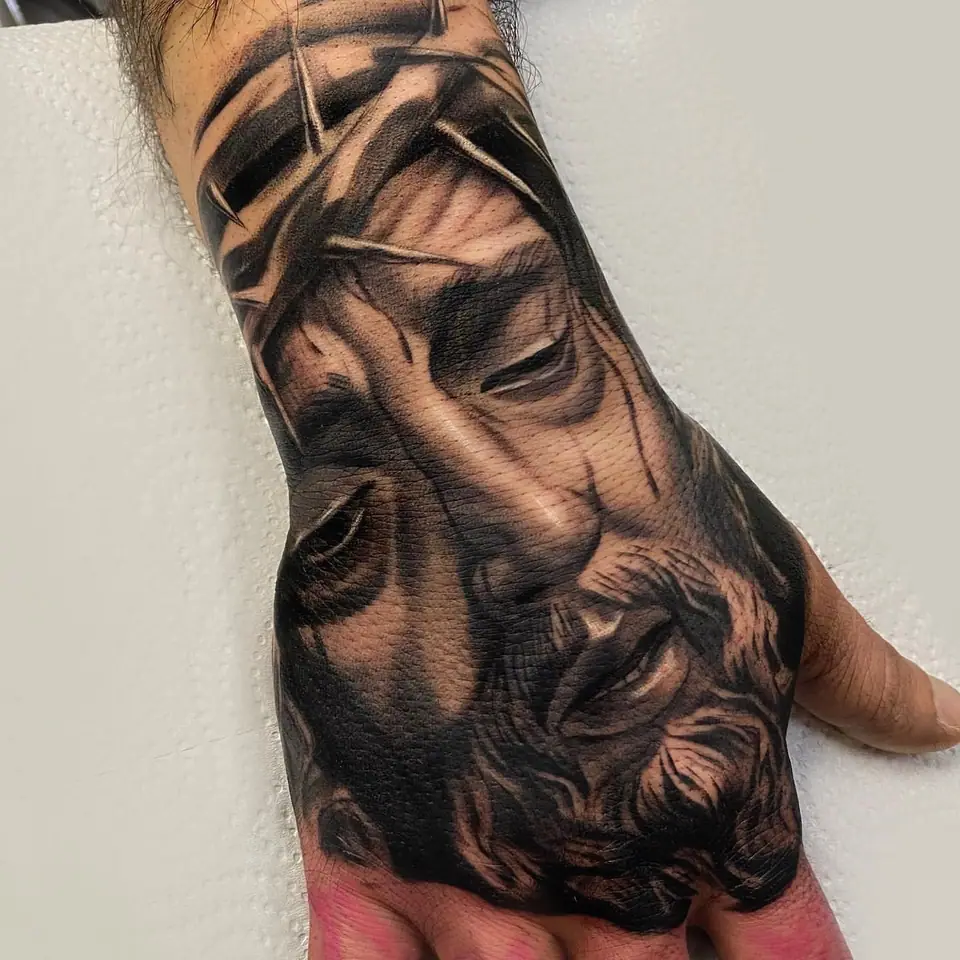 Tatuaje chicano en blanco y negro con rostro de Jesús con corona de espinas en la mano