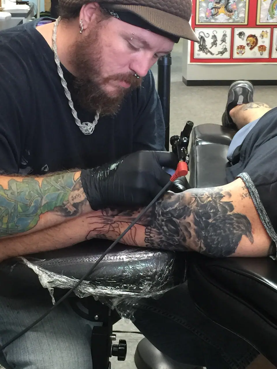 Tatuador trabajando un tatuaje a color en el antebrazo