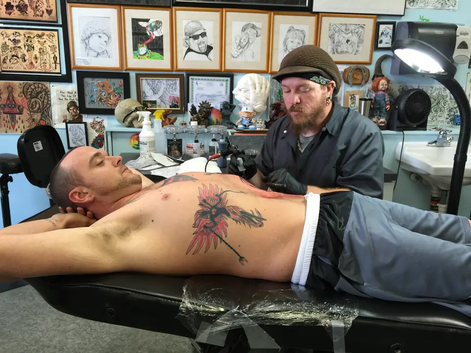 Tatuador trabajando sobre la zona de las costillas