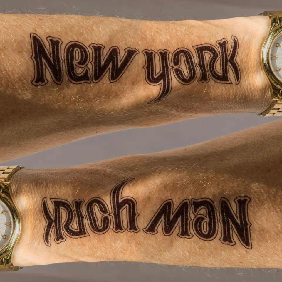 Tatuaje de letras (ambigrama) en el antebrazo en etapa de curación, con la piel enrojecida y con textura de costra