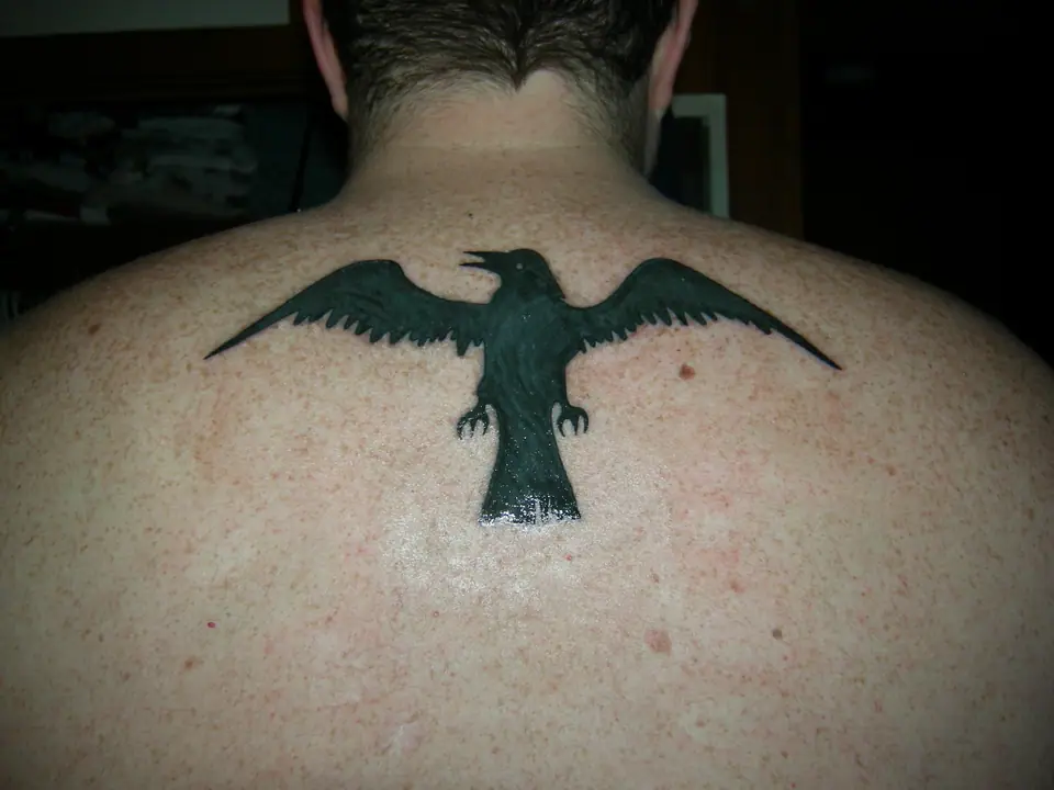 Tatuaje de un cuervo con las alas extendidas en la espalda