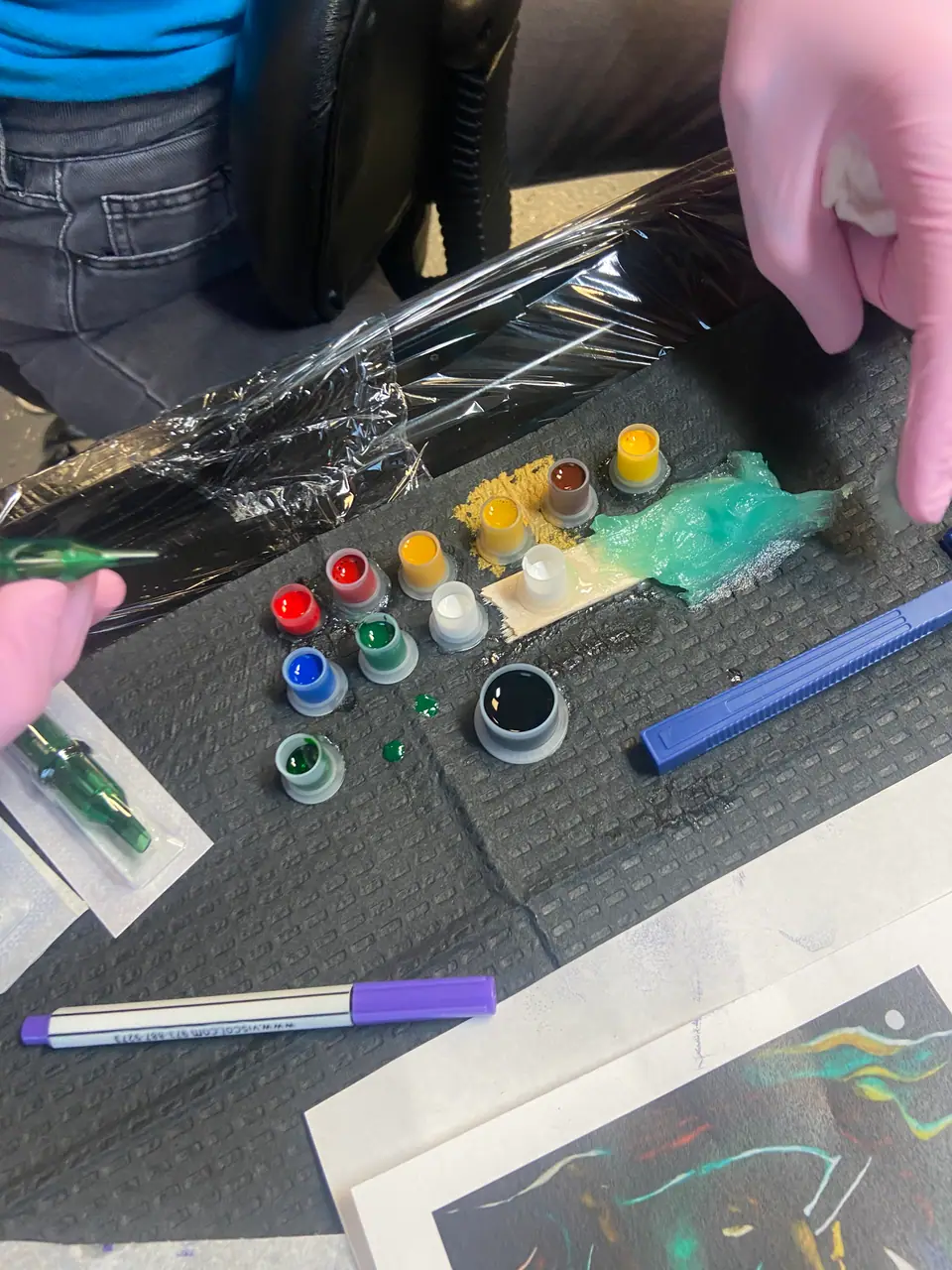 Tintas en vasos descartables y cartucho de agujas nuevo sobre una bandeja cubierta con film