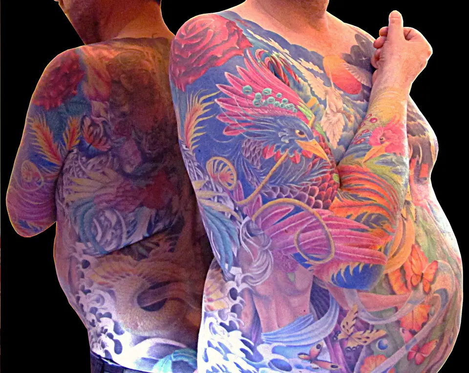 Tatuaje de un ave fénix a color en espalda y brazo