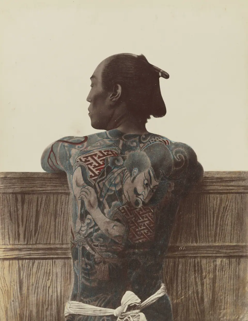 Fotografía histórica (Japón, fines del siglo XIX) de un hombre con un tatuaje tradicional que le cubre la espalda