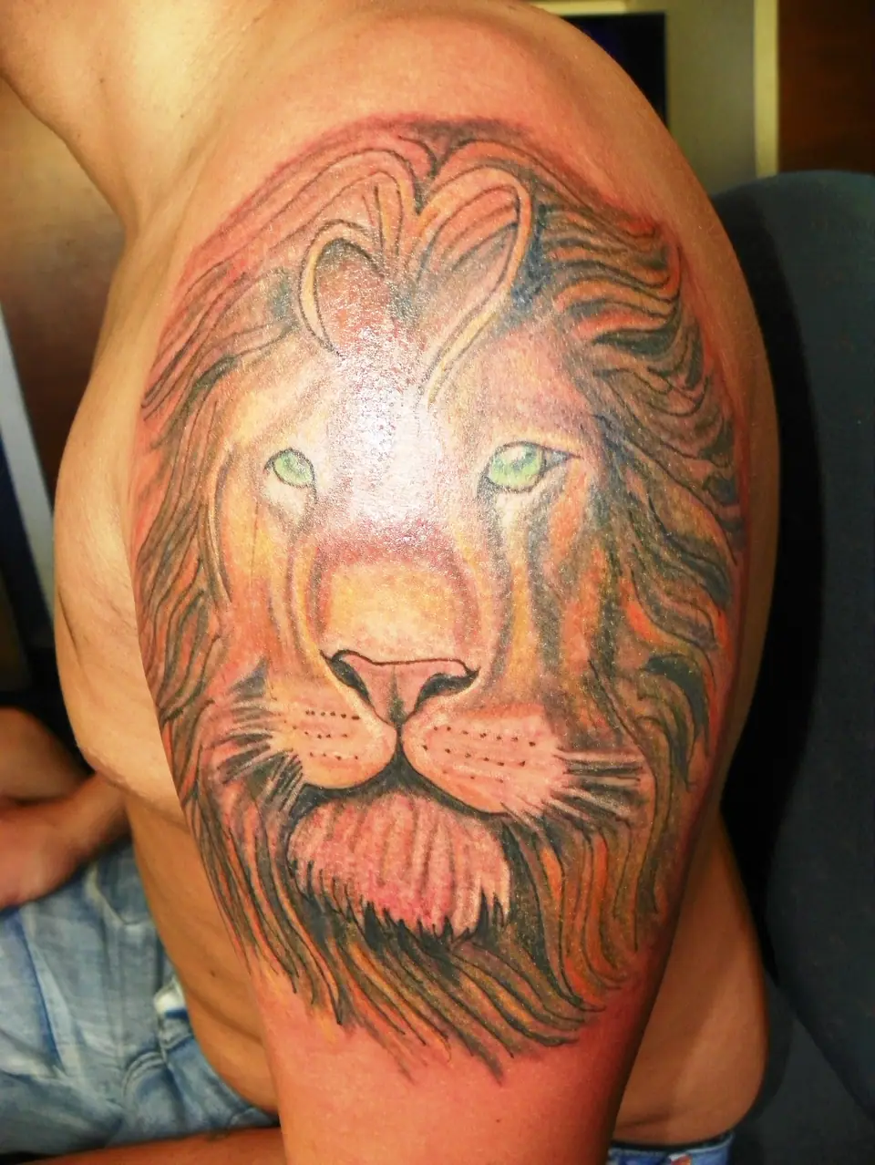 Tatuaje de una cabeza de león realista en el hombro, símbolo de fuerza