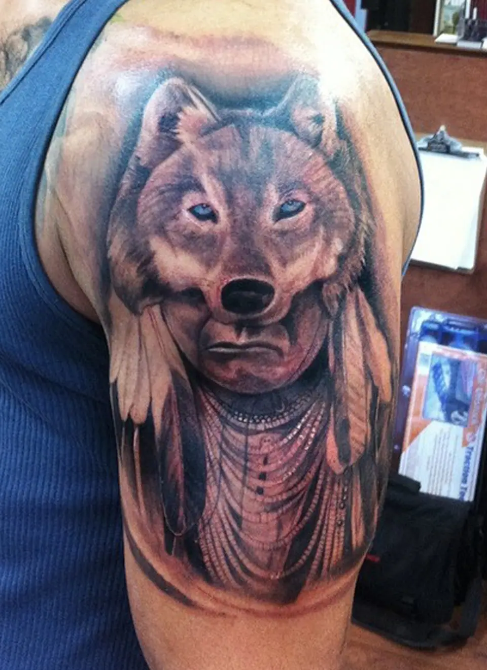 Tatuaje de cabeza de lobo con tocado de plumas en el hombro