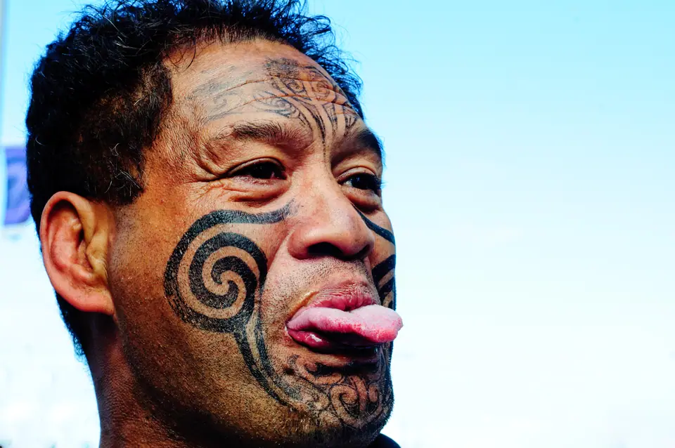 Hombre maorí con moko (tatuaje facial tradicional) completo