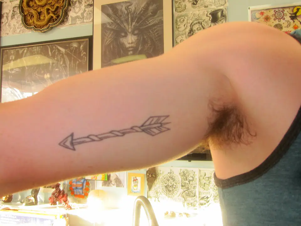 Tatuaje minimalista de una flecha en el brazo