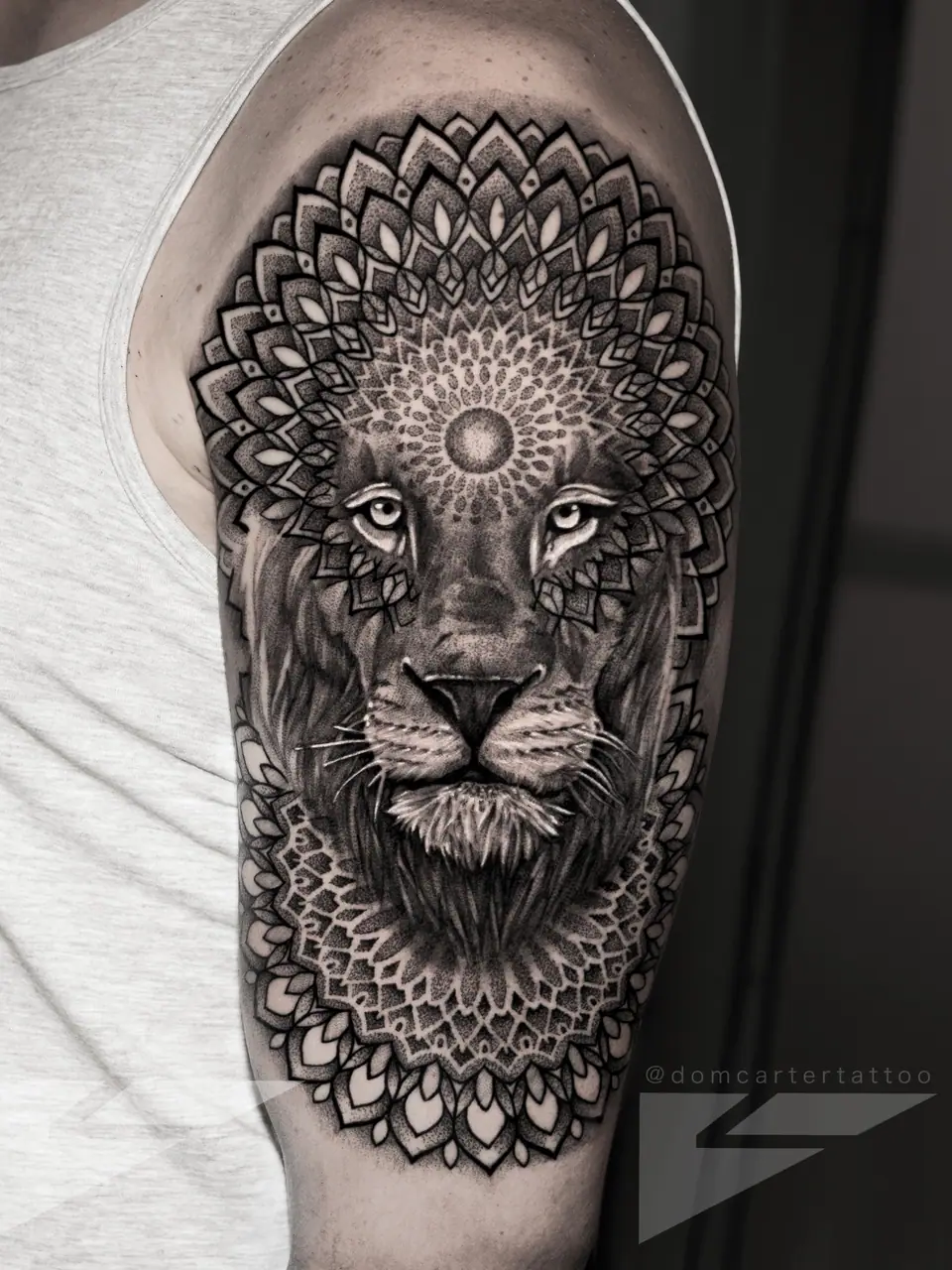 Tatuaje ornamental de un león enmarcado en un mandala, en el brazo