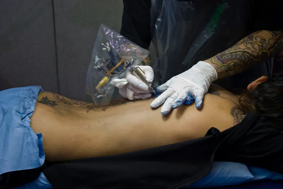 Tatuador trabajando sobre la espalda baja