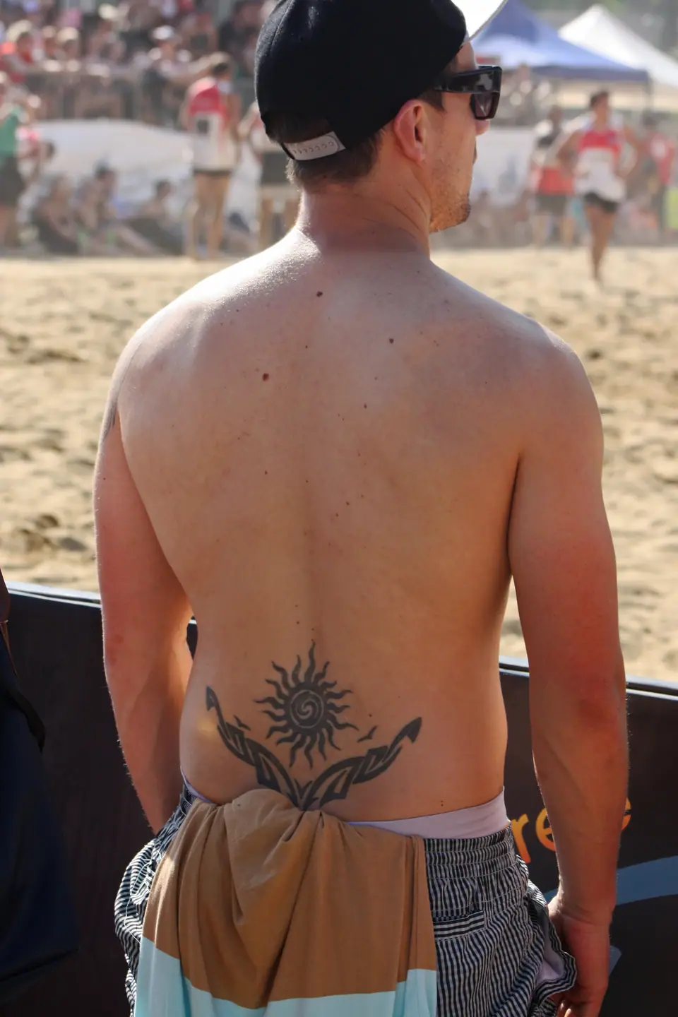 Tatuaje de sol en la espalda baja de un hombre en la playa