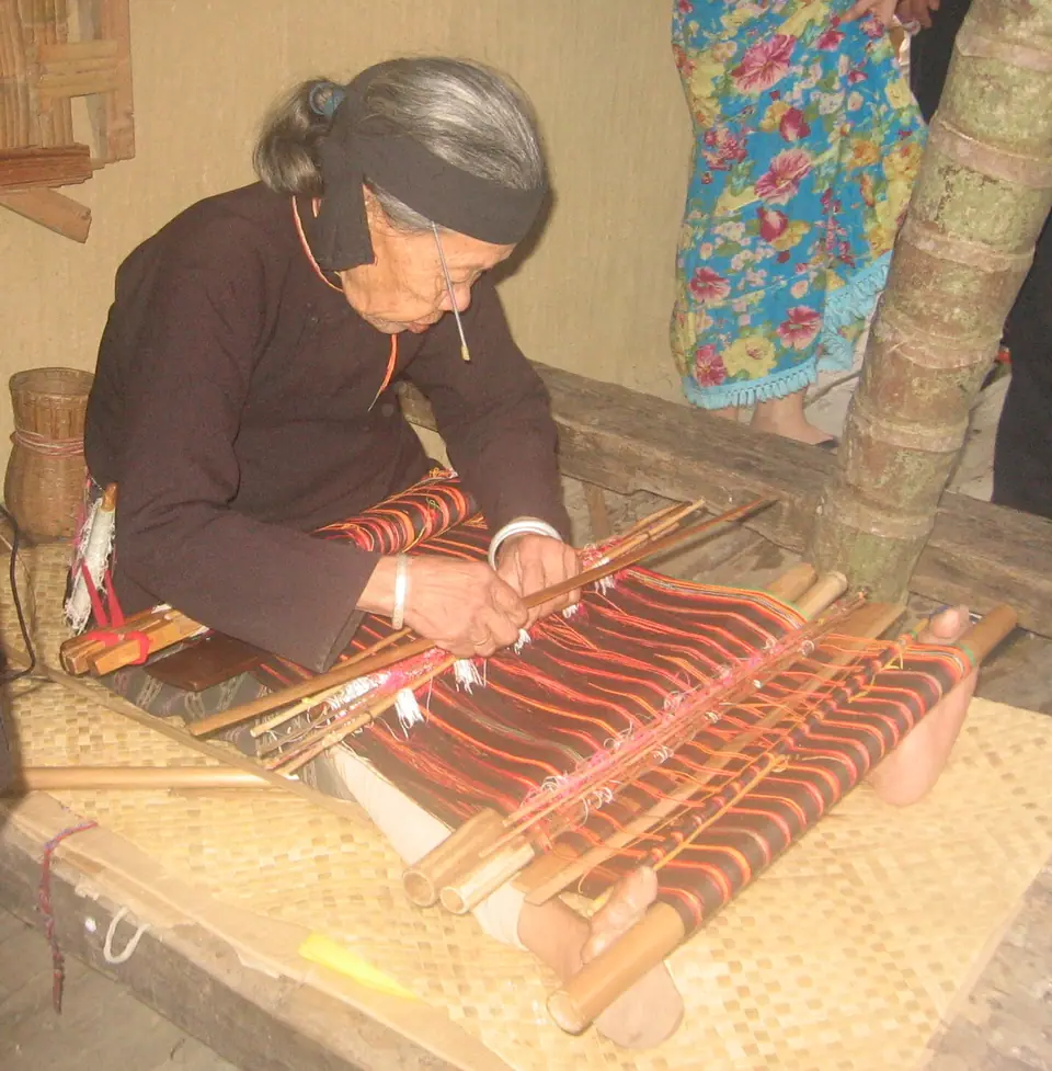 Mujer del pueblo Li tejiendo brocado tradicional en un telar de cintura, en Hainan, China